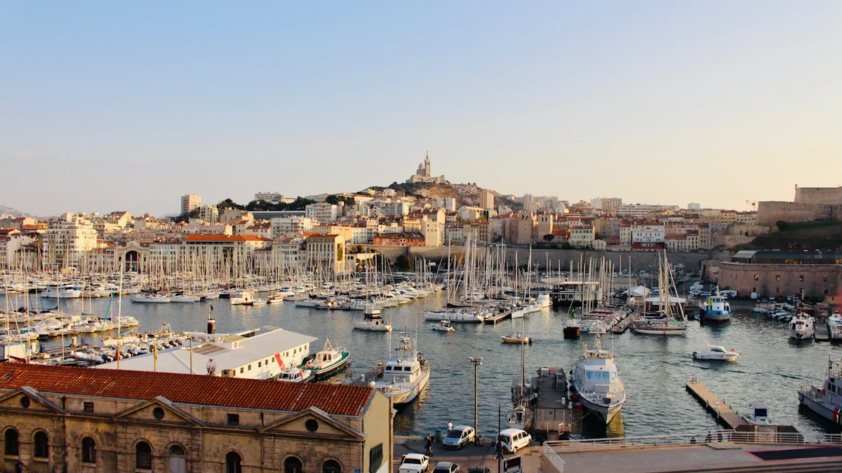Vue panoramique sur le Vieux-Port de Marseille avec la basilique Notre-Dame de la Garde en arrière-plan sous une lumière de fin de journée.