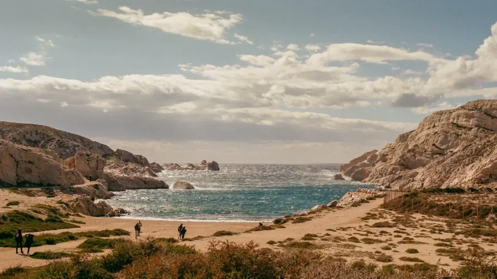 Vue panoramique d'une plage rocheuse naturelle à Marseille avec des baigneurs.