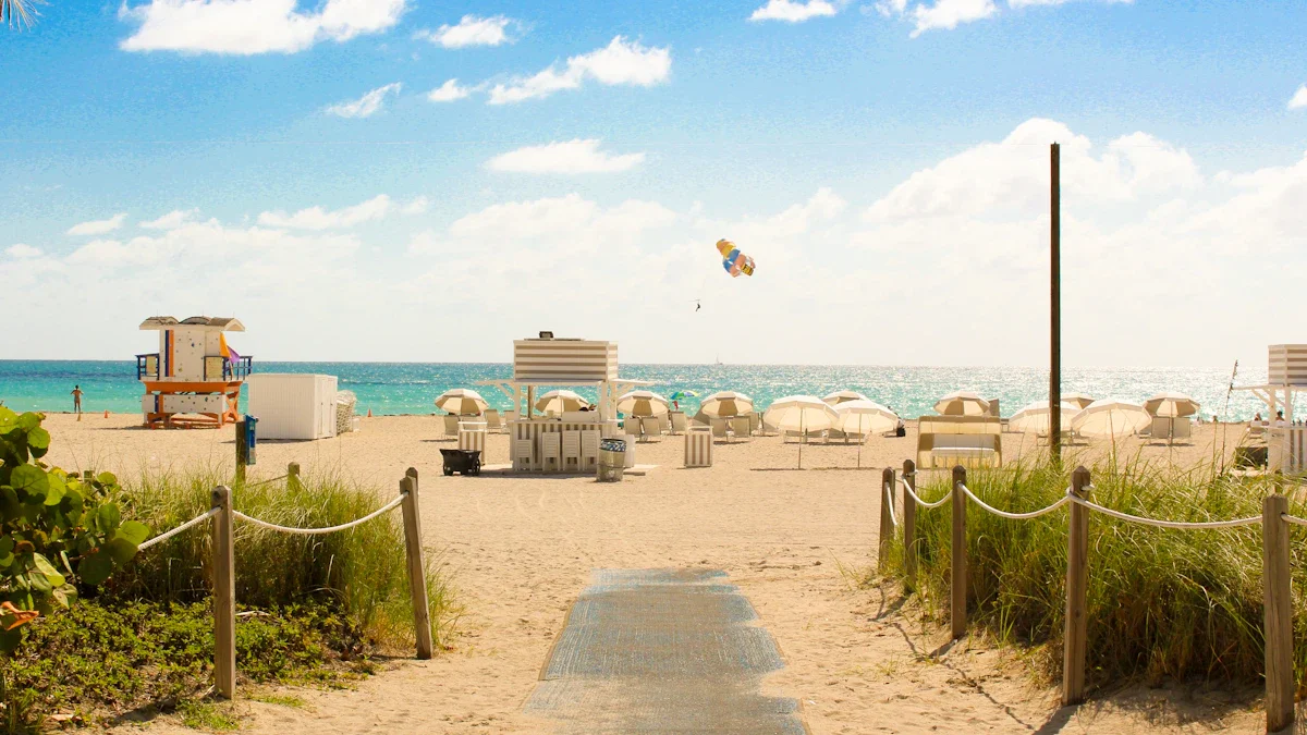 Un sentier aménagé menant vers une plage ensoleillée avec un poste de secours et des parasols.