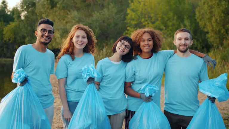 Groupe de bénévoles souriants tenant des sacs de déchets lors d'une opération de nettoyage des berges du Lez à Montpellier.