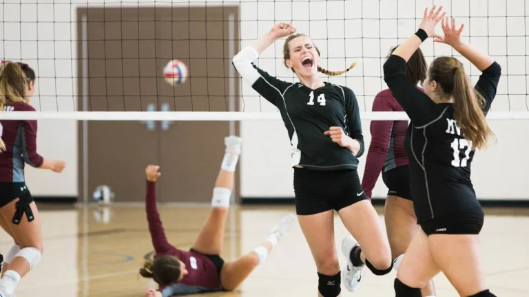Une joueuse de volley-ball exulte de joie après une victoire, entourée de ses coéquipières.
