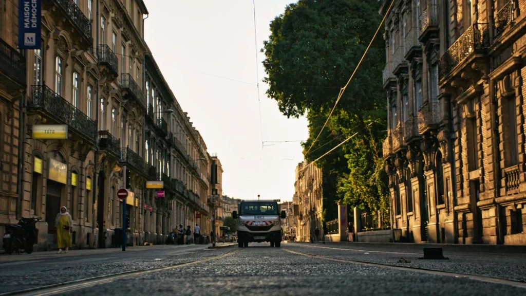 Une rue ensoleillée de Montpellier bordée d'immeubles classiques avec la Maison des Relations Internationales.