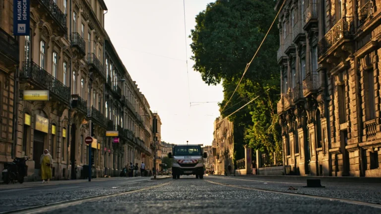 Une rue ensoleillée de Montpellier bordée d'immeubles classiques avec la Maison des Relations Internationales.