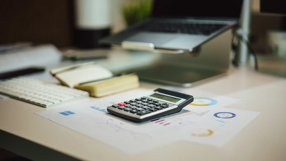 Une calculatrice posée sur des graphiques financiers et des factures à côté d'un ordinateur portable dans un bureau.