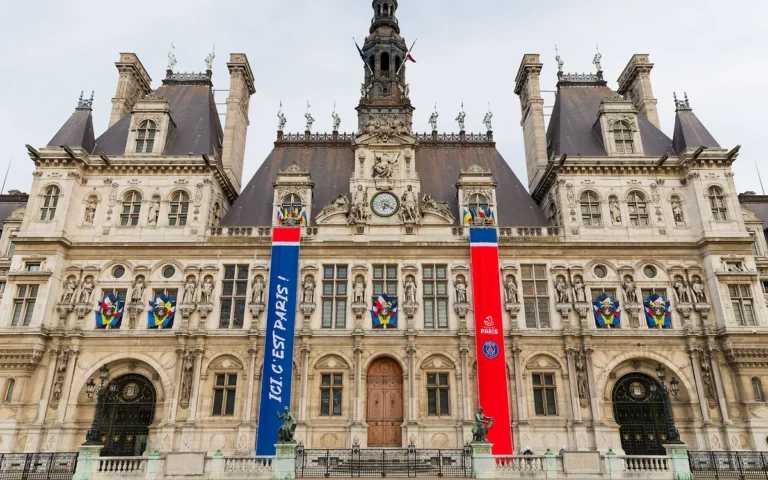 Façade de l'Hôtel de Ville de Paris ornée de deux grandes bannières verticales aux couleurs du PSG.