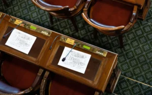 Vue en plongée de bureaux en bois avec microphones et documents du Conseil de Paris.