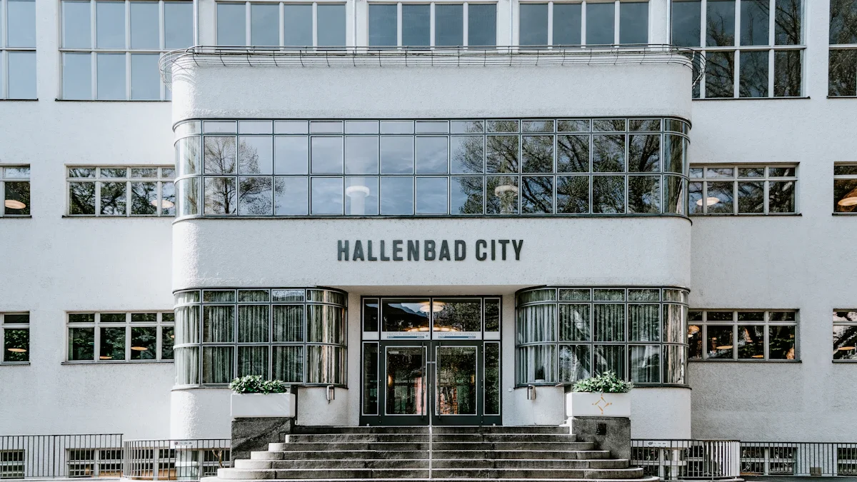 Façade blanche d'une piscine municipale urbaine avec de larges baies vitrées et escaliers.