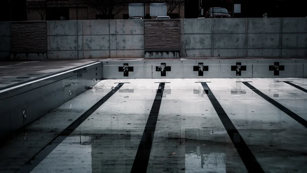 Une photo en noir et blanc d'un grand bassin de piscine olympique vide et sec.
