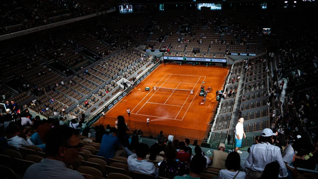 Vue plongeante sur un court de tennis en terre battue lors d'un tournoi majeur.