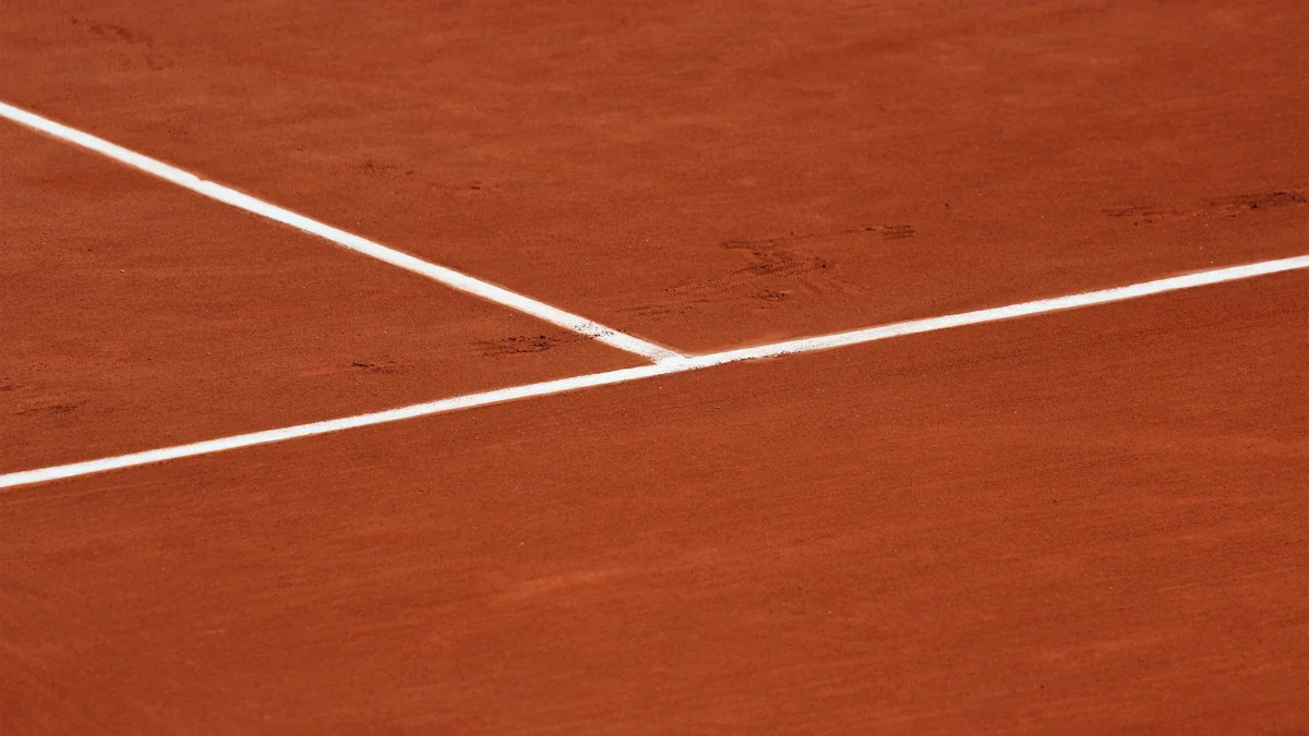 Lignes blanches sur la terre battue emblématique du court de tennis parisien.