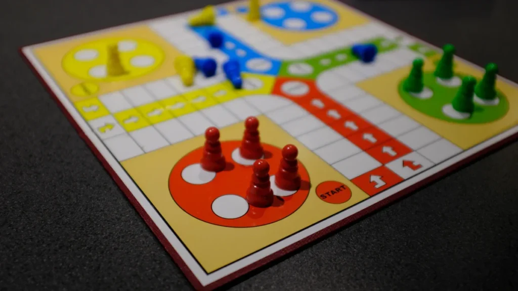 Gros plan sur un plateau de jeu de société coloré avec des pions rouges, jaunes et verts.