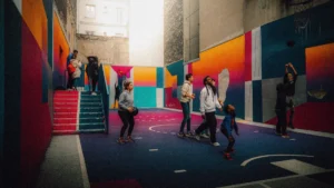 Un groupe de jeunes jouant au basket-ball sur un terrain urbain extrêmement coloré et artistique, illustrant le dynamisme des loisirs pour la jeunesse.