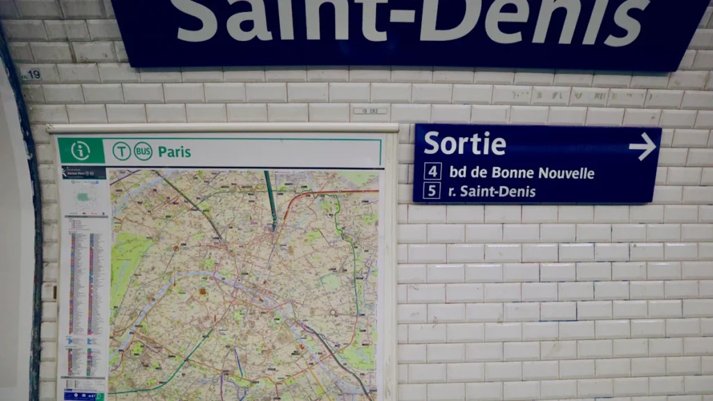 Panneau de signalisation Saint-Denis dans une station de métro avec plan de ville et sortie.