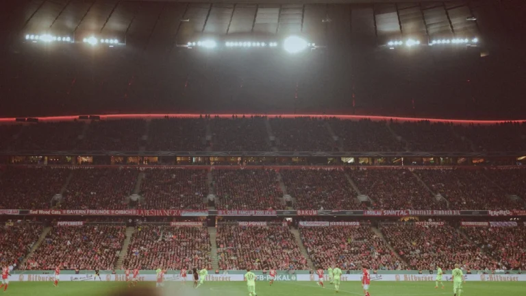 Une tribune comble vibrant au rythme d'un match de football nocturne, illustrant la ferveur retrouvée des supporters.