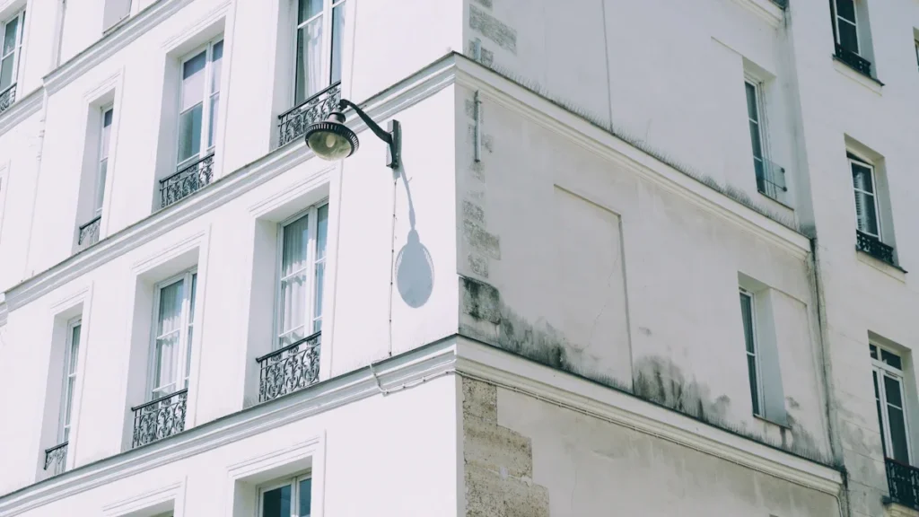 Façade d'un immeuble blanc élégant à l'architecture française typique sous un ciel bleu clair.