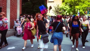 Une foule joyeuse et engagée défilant pour la Marche des fiertés avec des drapeaux de la communauté LGBTQIA+.