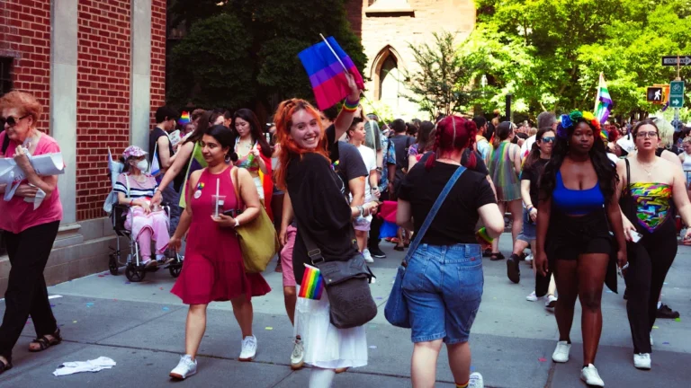 Une foule joyeuse et engagée défilant pour la Marche des fiertés avec des drapeaux de la communauté LGBTQIA+.