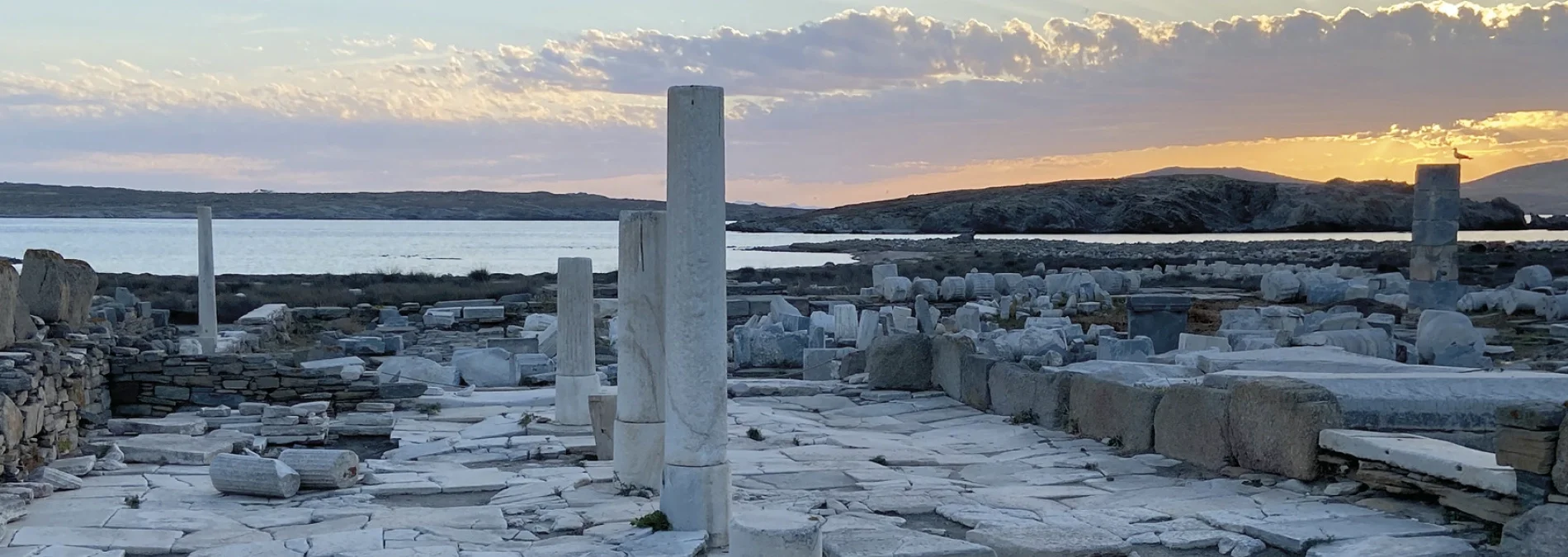 Ruines antiques de marbre blanc au bord de la mer sous un ciel de crépuscule.