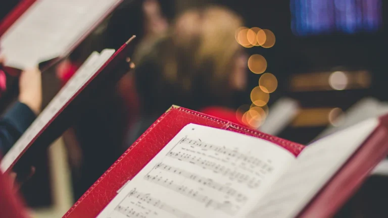 Gros plan sur une partition de chant choral tenue dans un classeur rouge par un choriste.