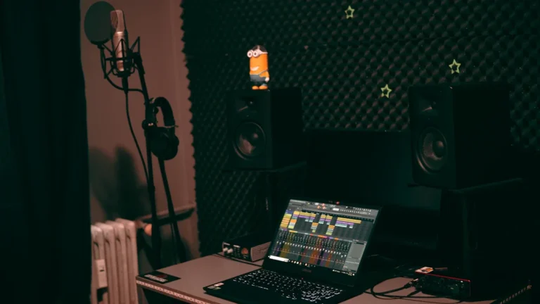 Un équipement de studio d'enregistrement mobile comprenant un ordinateur portable avec un logiciel de mixage, des enceintes et un microphone.