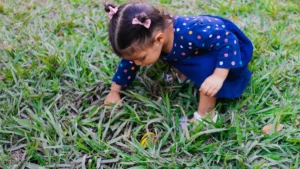 Une petite fille concentrée cherchant un indice dans l'herbe lors d'une chasse aux trésors.