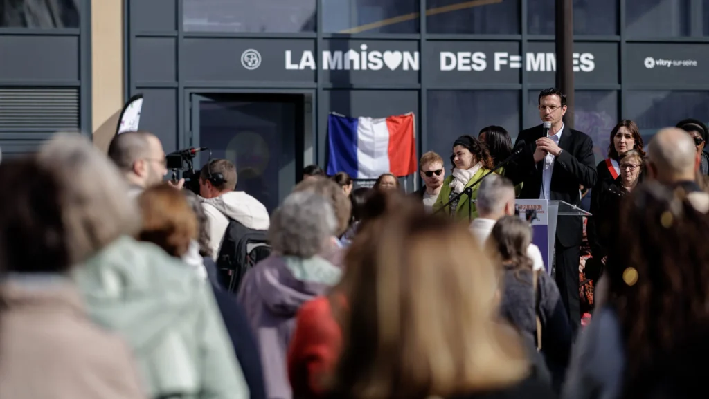 Un homme en costume s'exprime devant La Maison des Femmes à Vitry-sur-Seine devant un public.