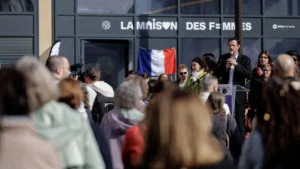 Un homme en costume s'exprime devant La Maison des Femmes à Vitry-sur-Seine devant un public.