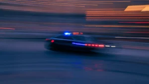 Une voiture de police patrouillant rapidement dans une rue sombre en ville.