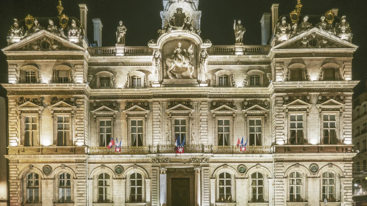 L'Hôtel de Ville de Lyon illuminé sous un ciel nocturne, emblème de la municipalité.