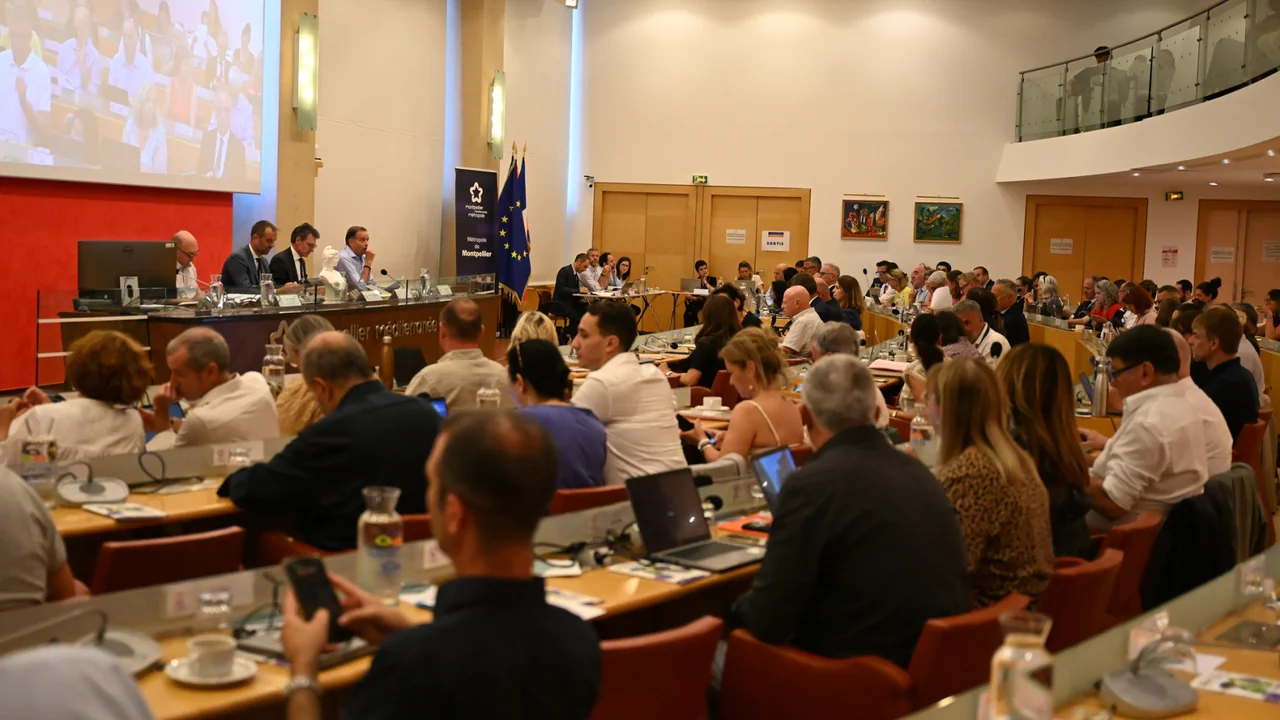 Une vue large d'une salle de conférence avec de nombreux participants assis aux tables.