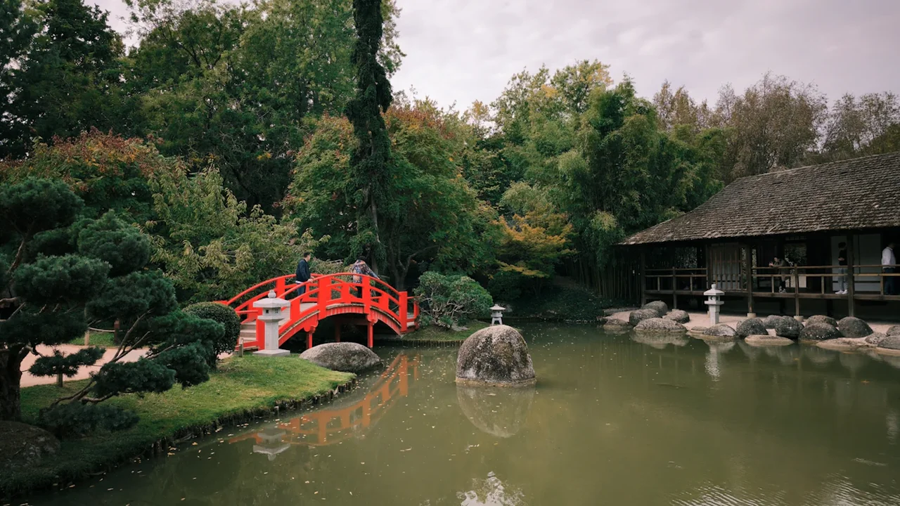 Jardin japonais à Toulouse avec son pont rouge emblématique au-dessus d'un bassin.