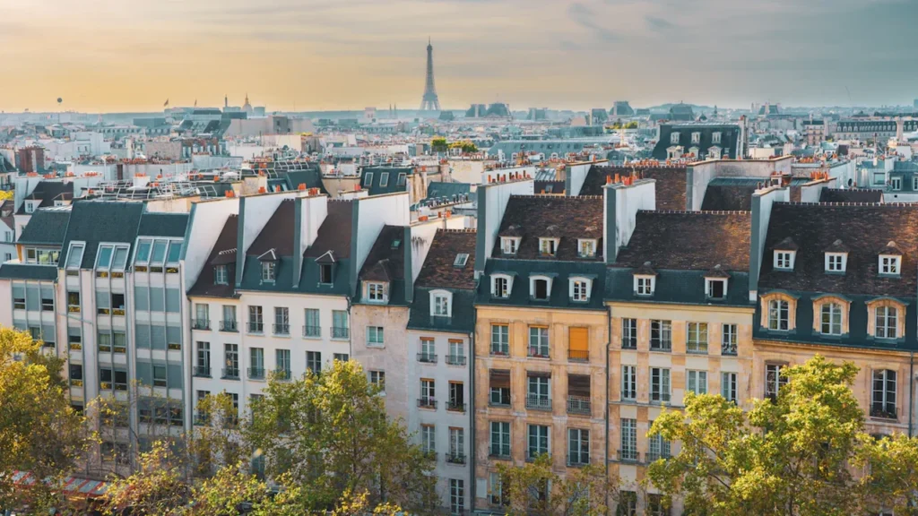 Vue panoramique des toits de Paris avec la tour Eiffel à l'horizon.