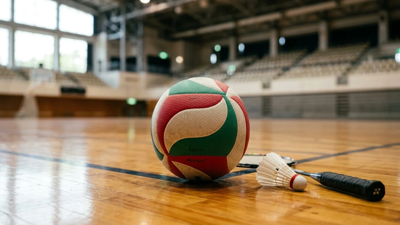 Un ballon de volley-ball multicolore et un volant de badminton posés sur un parquet sportif.
