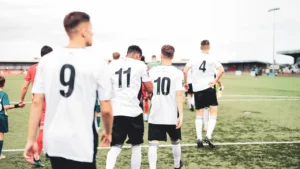 Joueurs de football marchant sur le terrain avant le match, vue de dos.