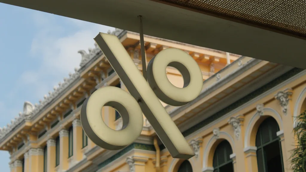 Symbole de pourcentage suspendu devant un bâtiment classique à l'architecture européenne traditionnelle.