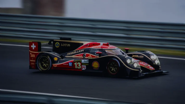 Une voiture de course rouge et noire sur la piste du Mans.