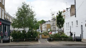 Vue d'une rue urbaine avec des bâtiments et des aménagements paysagers verts.