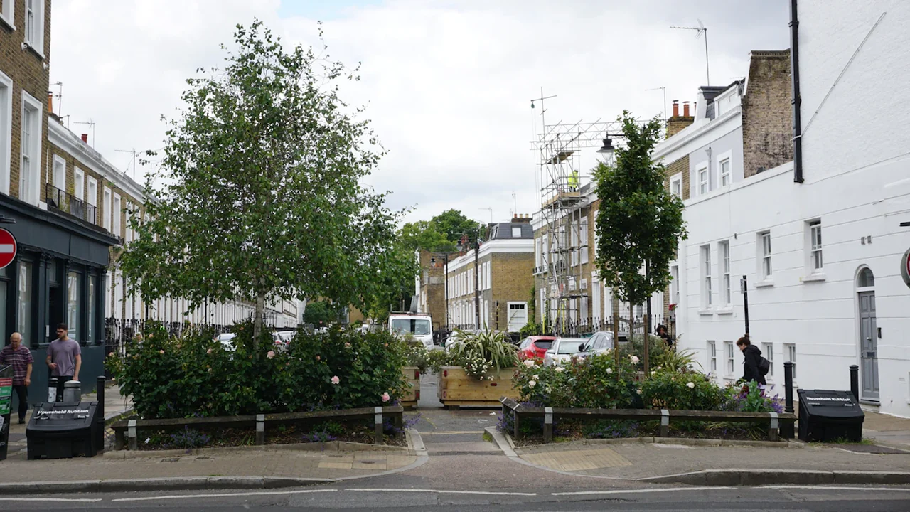 Vue d'une rue urbaine avec des bâtiments et des aménagements paysagers verts.