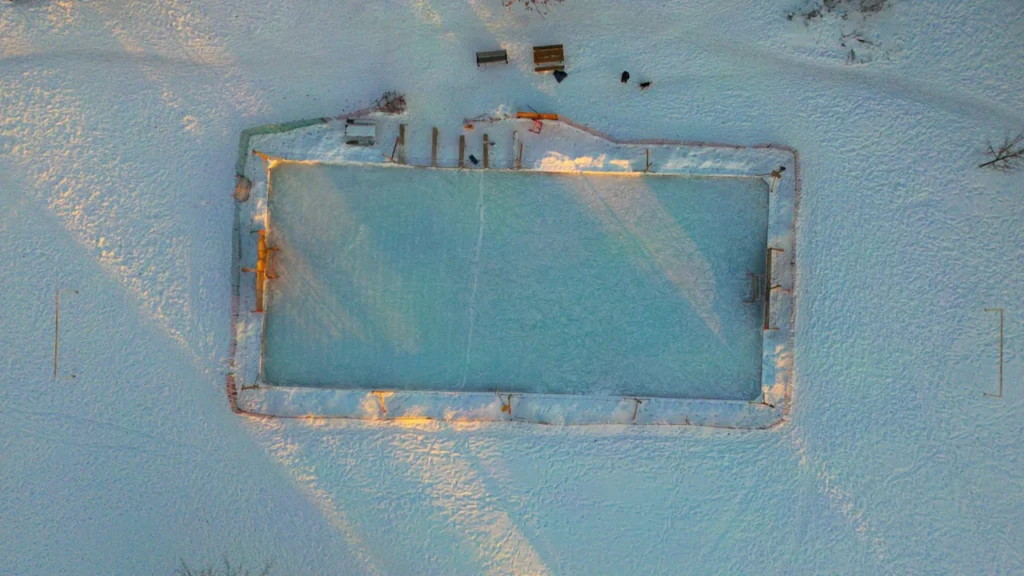 Vue aérienne d'une patinoire extérieure installée dans un environnement urbain hivernal.