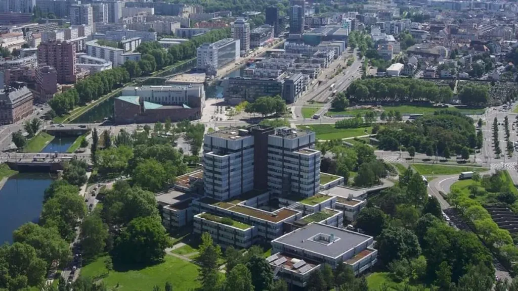 Vue aérienne d'un complexe de bureaux moderne entouré d'espaces verts et d'un canal urbain.