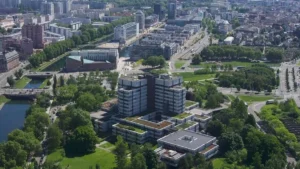 Vue aérienne d'un complexe de bureaux moderne entouré d'espaces verts et d'un canal urbain.