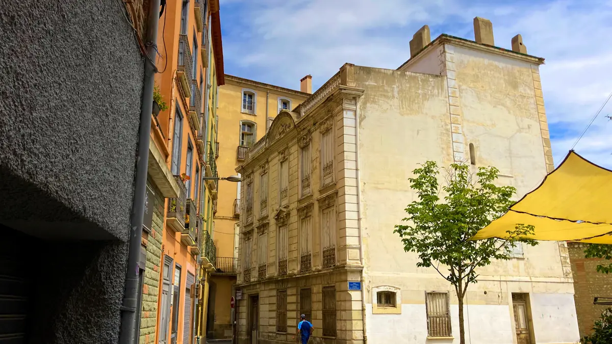 Rues anciennes de Perpignan avec architecture traditionnelle et ambiance estivale ensoleillée.