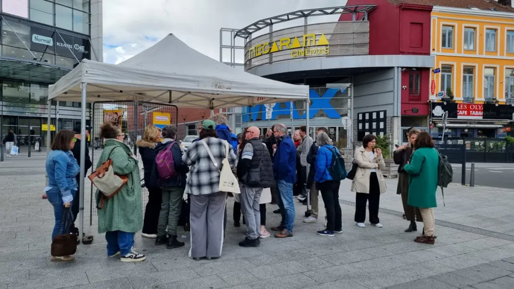 Un groupe de personnes discute debout sous un barnum blanc devant le cinéma Mégarama.