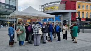 Un groupe de personnes discute debout sous un barnum blanc devant le cinéma Mégarama.