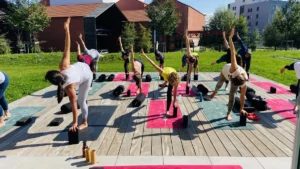 Un groupe de personnes pratiquant le yoga en plein air sur une terrasse en bois.