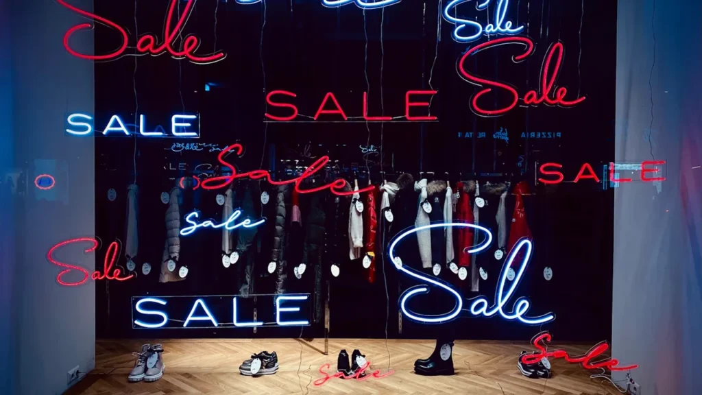Panneau lumineux affichant le mot 'Soldes' dans une vitrine de magasin décorée.