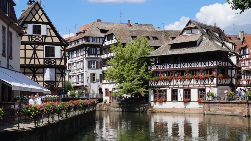 Maisons à colombages alsaciennes traditionnelles au bord d'un canal calme à Strasbourg.