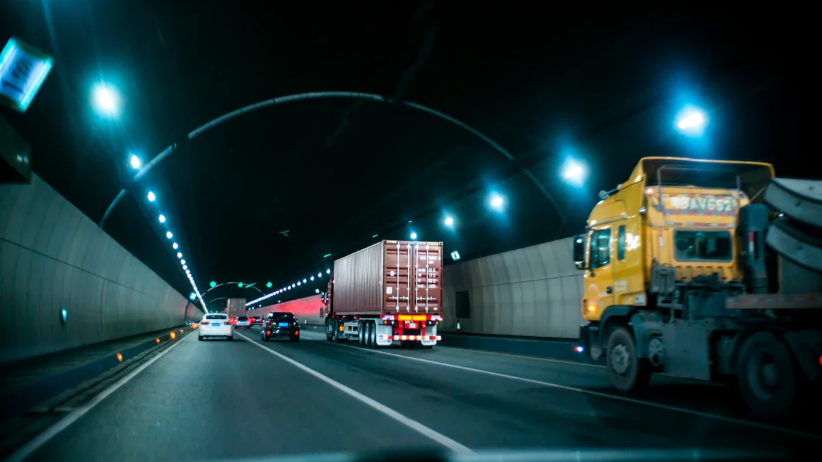Un camion jaune circulant de nuit dans un tunnel urbain très éclairé.