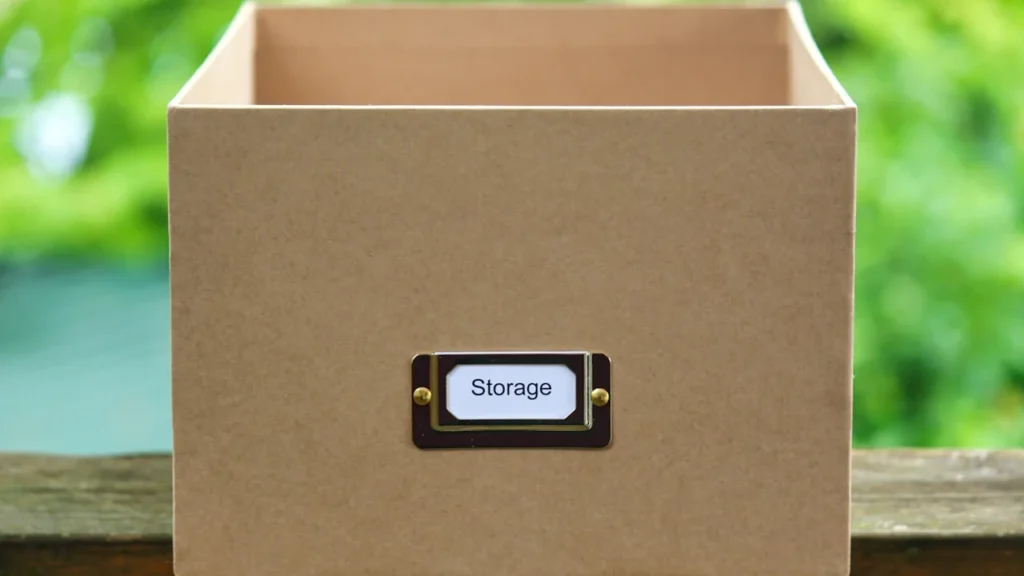 Une boîte de rangement en carton beige avec une étiquette métallique indiquant le mot Storage.