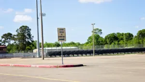 Panneau de signalisation sur un parking vide devant un stade de sport en extérieur.
